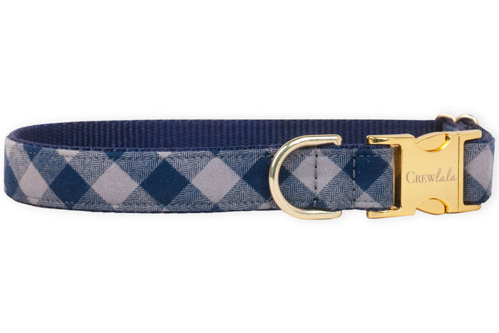 A stylish navy plaid dog collar with metal hardware and an engraved buckle, blending everyday durability with upscale charm for the pup who likes to strut in style.