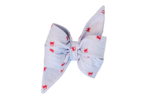 A light blue fabric girl dog belle bow with pointed ends, decorated with a repeating red crab pattern. The bow is neatly folded and structured, adding a nautical-themed flair.