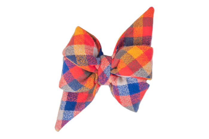 Colorful plaid bow featuring intersecting checks of red, blue, orange, styled with two full loops and two tapered ends for a bold look.